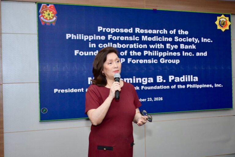 Dra. Dominga B. Padilla speaking with a microphone in front of the proposed research title slide